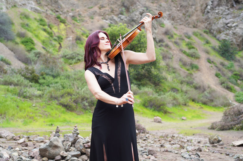 A photo of Nathalie Bonin playing violin outdoors.